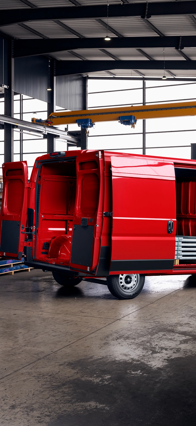 Rear three-quarter view of a red Citroën Relay with open cargo doors inside a warehouse, highlighting large loading space, durability, and business versatility.