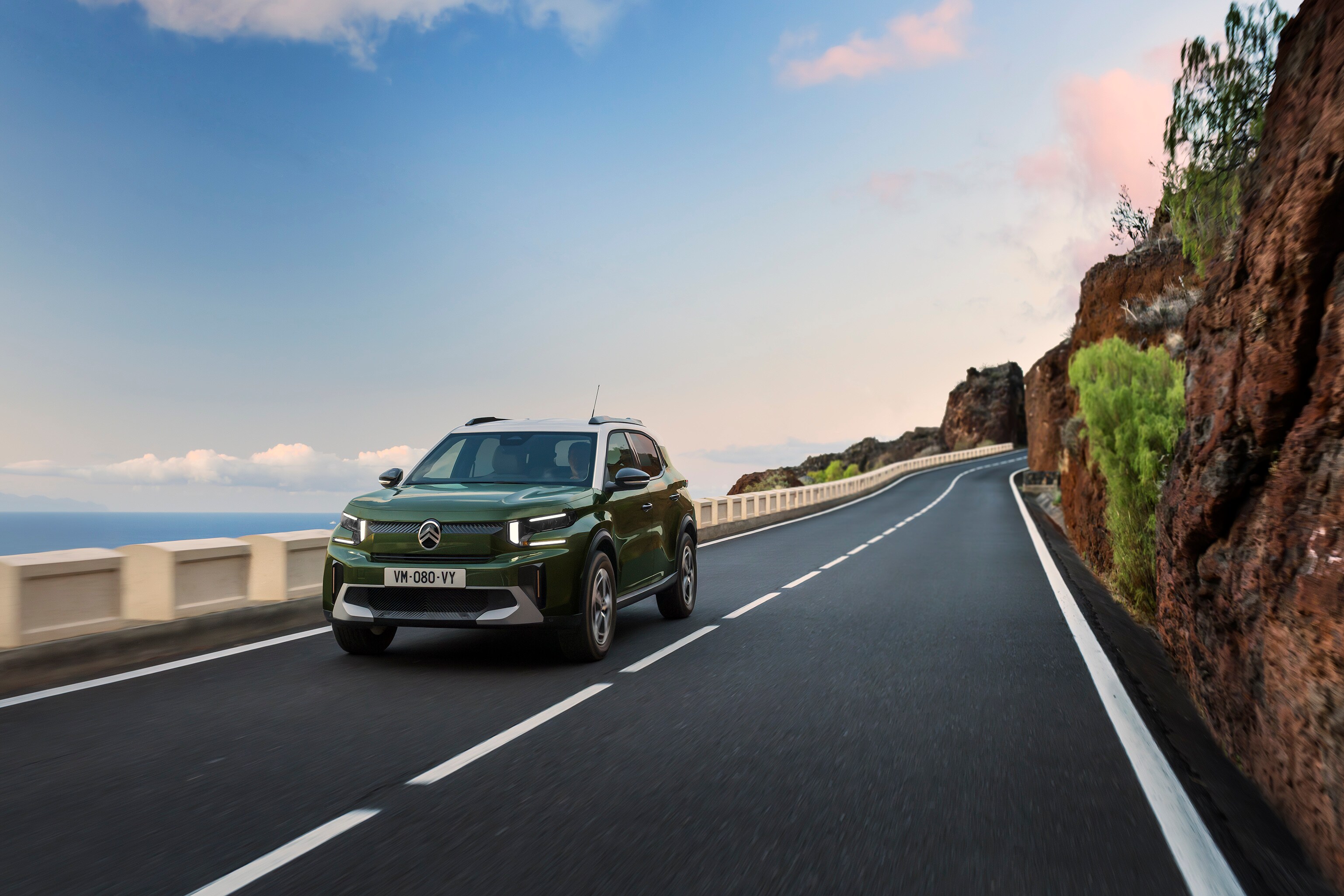 Front three‑quarter driving view of Citroën C3 compact SUV on a scenic road highlighting agile, confident and affordable everyday mobility.